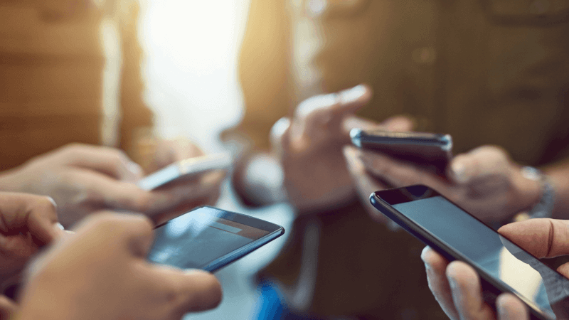 Roda de pessoas mexendo no celular.